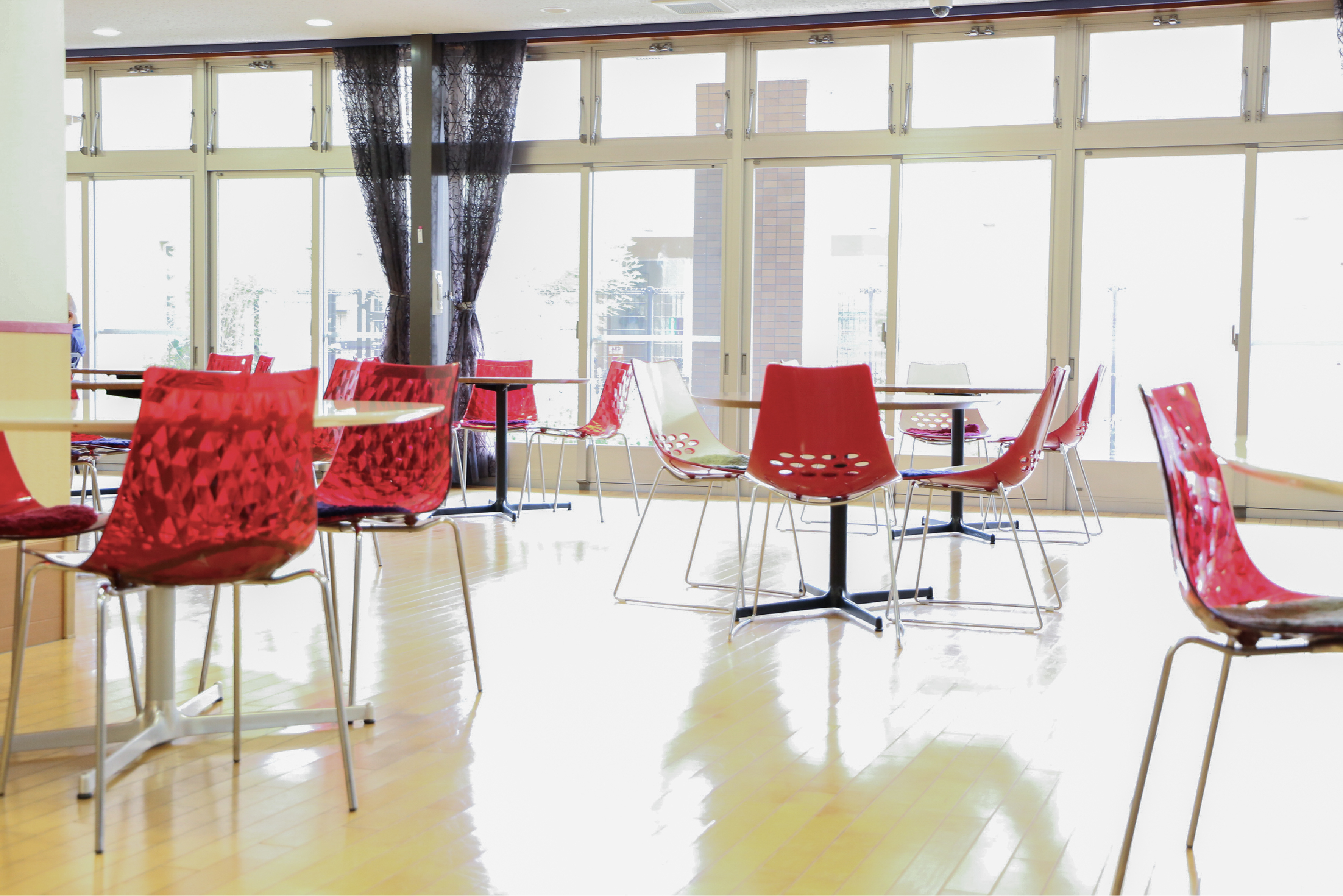 机と赤い椅子のある介護施設内風景写真