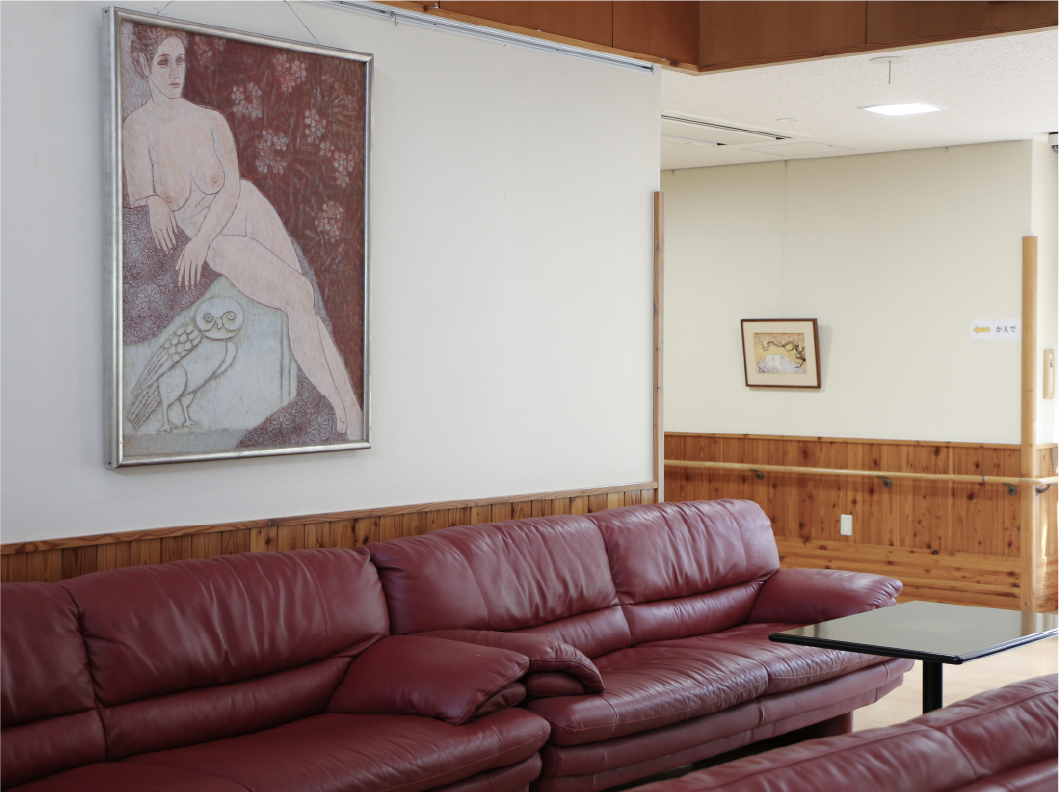 壁にかかった絵画とソファのある施設内風景写真